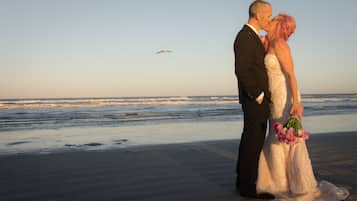 Een stel staat op het strand, met de oceaan op de achtergrond.
