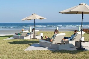 Uma área de estar à beira-mar, com espreguiçadeiras e guarda-sóis, com vista para o oceano.