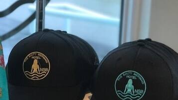 Deux casquettes noires, ornées de logos, sont posées sur une étagère en métal.