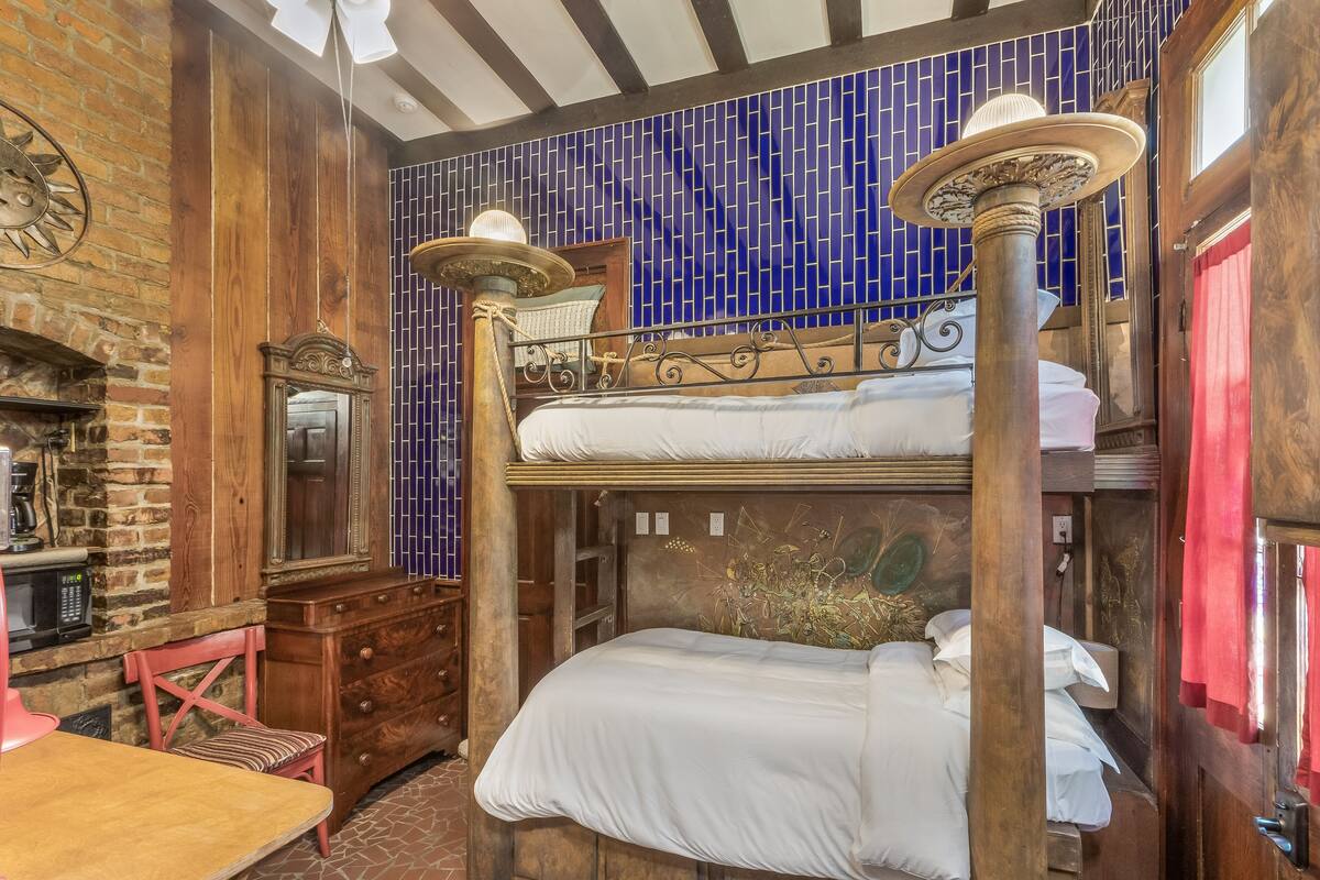 Quarto com beliche, mobiliário de madeira, parede de tijolos e parede revestida de azulejos azuis.