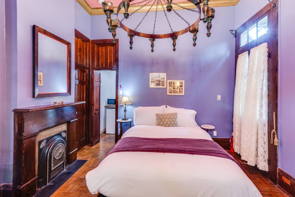 Quarto com uma cama grande, mobiliário de madeira, um candelabro e uma lareira.