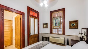 A bedroom with a bed, wooden doors, a radiator, and a ceiling fan. - Royal Barracks Guest House (New Orleans)