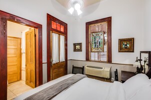 A bedroom with a bed, wooden doors, a radiator, and a ceiling fan.