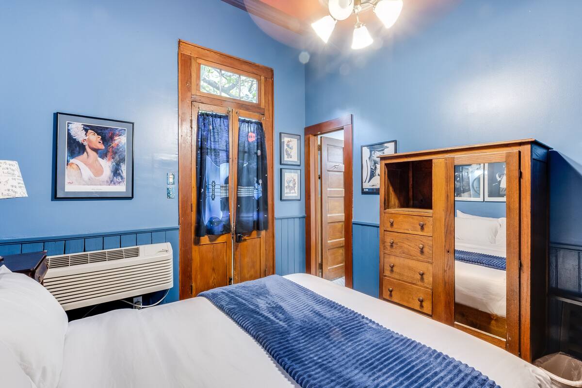 Quarto com cama, guarda-roupa de madeira e janela com cortinas.