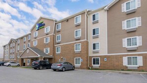 A multi-story hotel with a brick facade, multiple windows, and a parking lot with several cars.