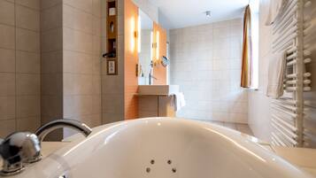 Ein modernes Badezimmer mit einer großen Badewanne, einem Waschtisch inklusive Spiegel und einem Handtuchhalter.