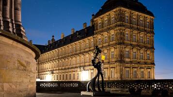 A historic building with classical architecture, a starry night sky, and a decorative metal sculpture in an open plaza.