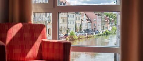 A room with a view of a canal and buildings through a window.