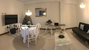 A living room with a TV, a dining table, chairs, a sofa, and a Christmas tree. - Edificio California en Centro Histórico (Lima)