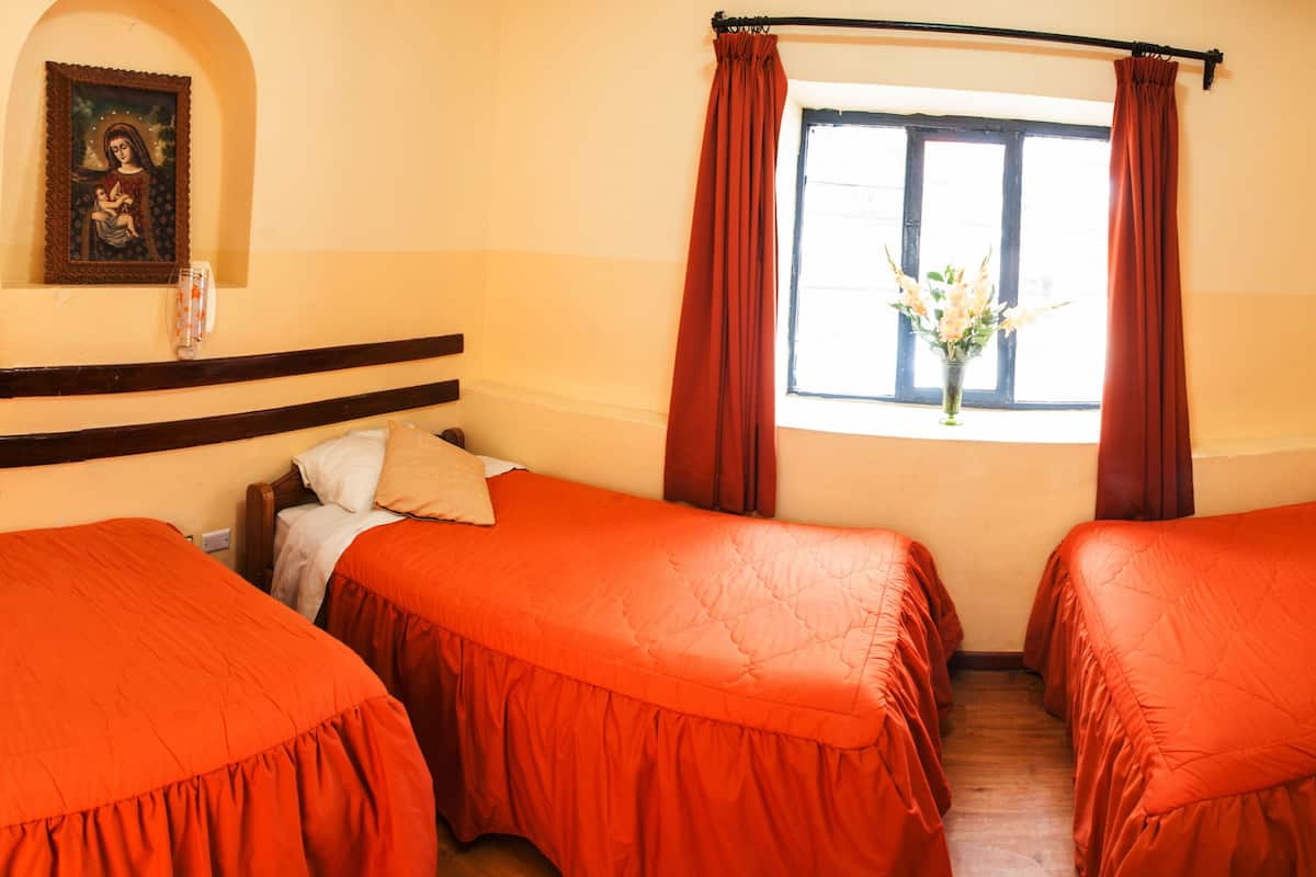 A hotel room with two beds, a window with curtains, a wall-mounted picture, and a wooden headboard.