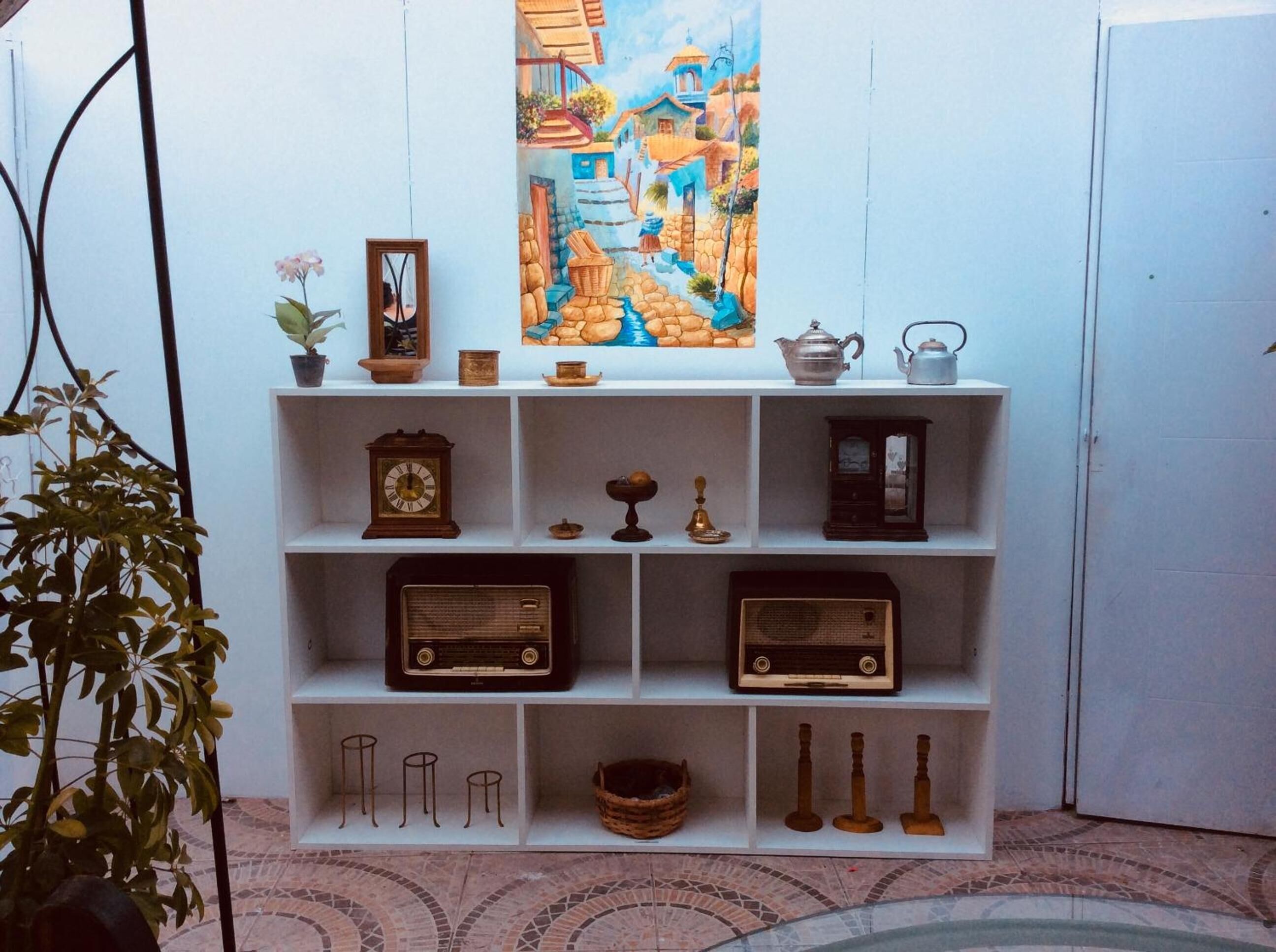 A shelf with various antique items including a clock, radios, and decorative objects.