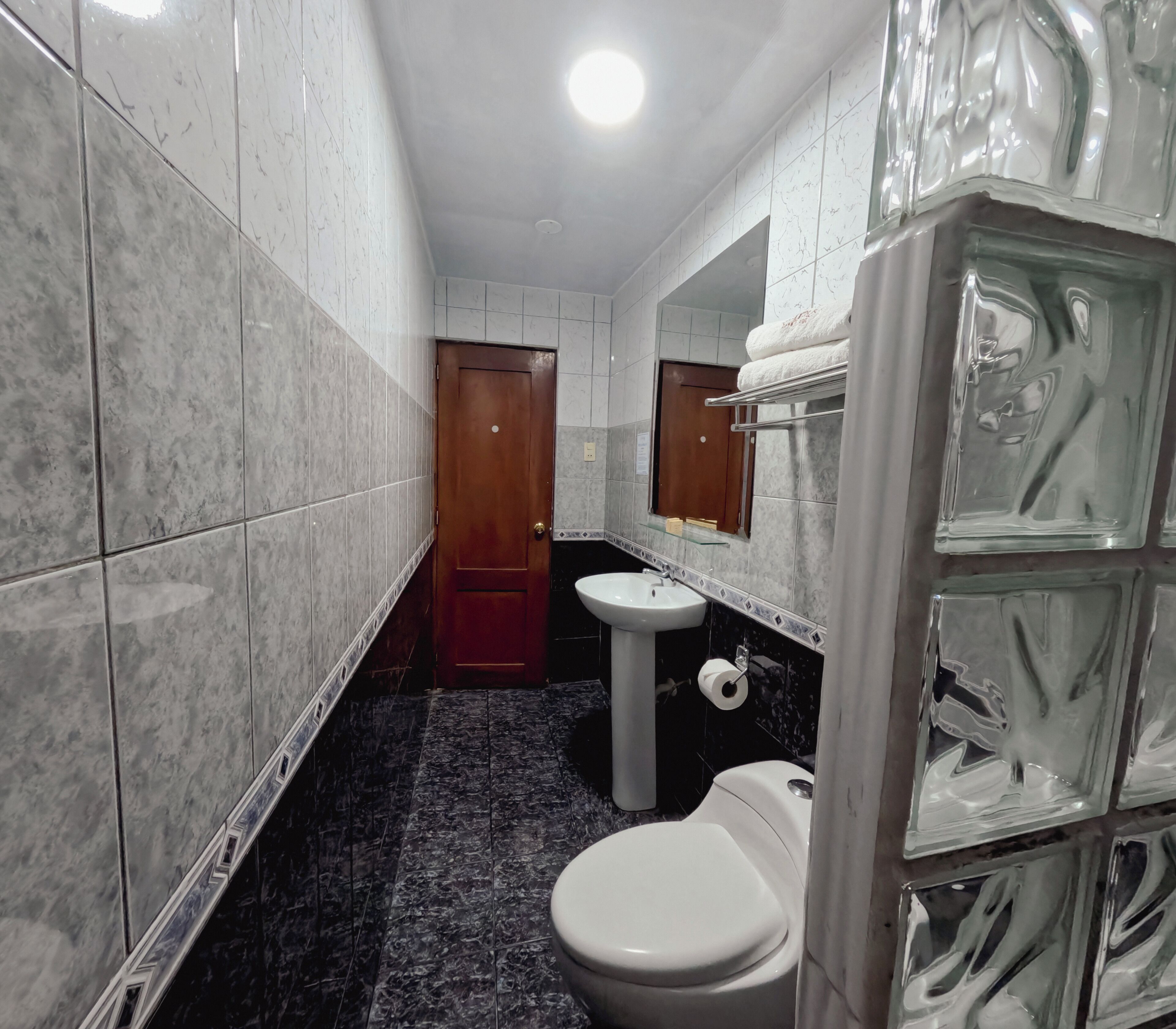 Un baño estrecho con inodoro, lavamanos y espejo.