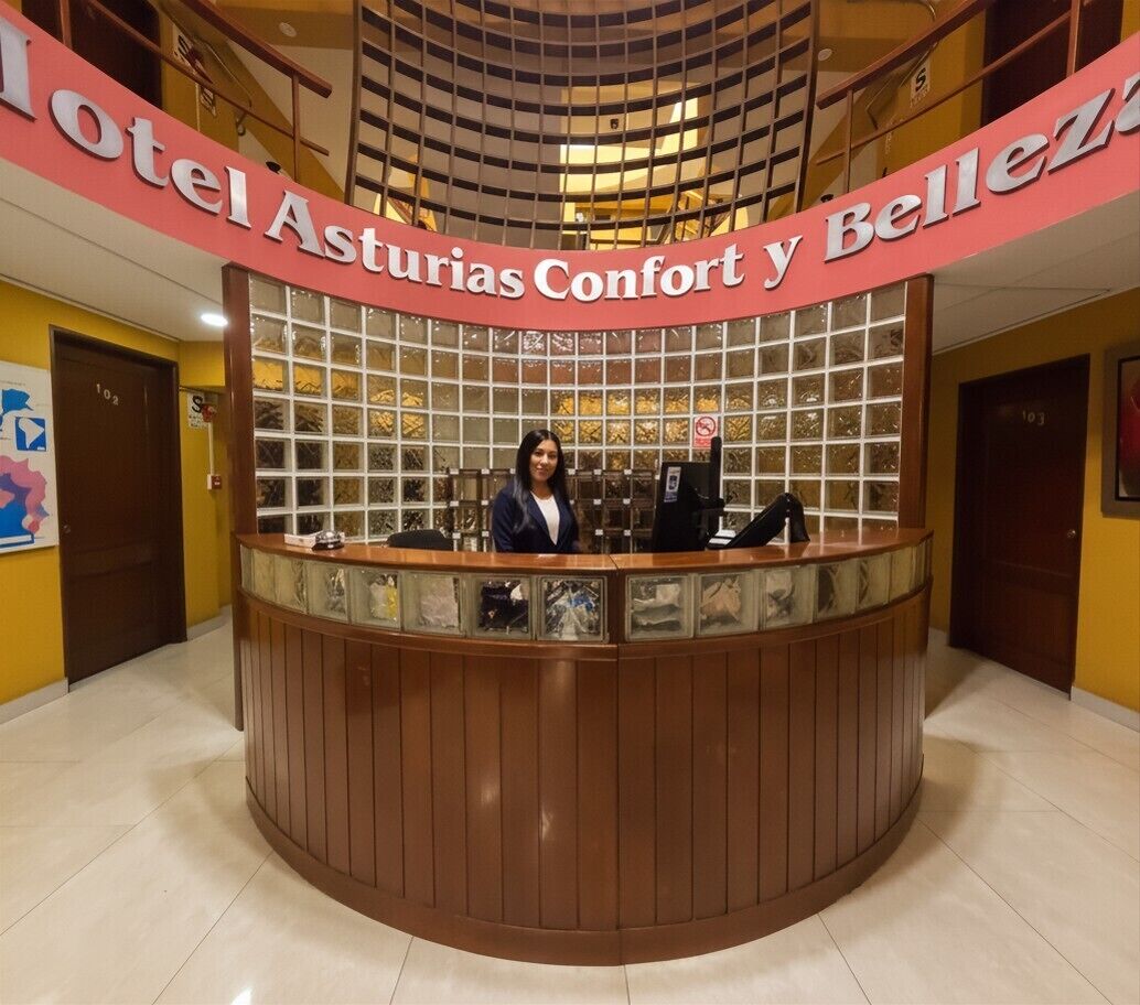 A hotel reception desk with a sign reading 'Hotel Asturias Confort y Belleza.'