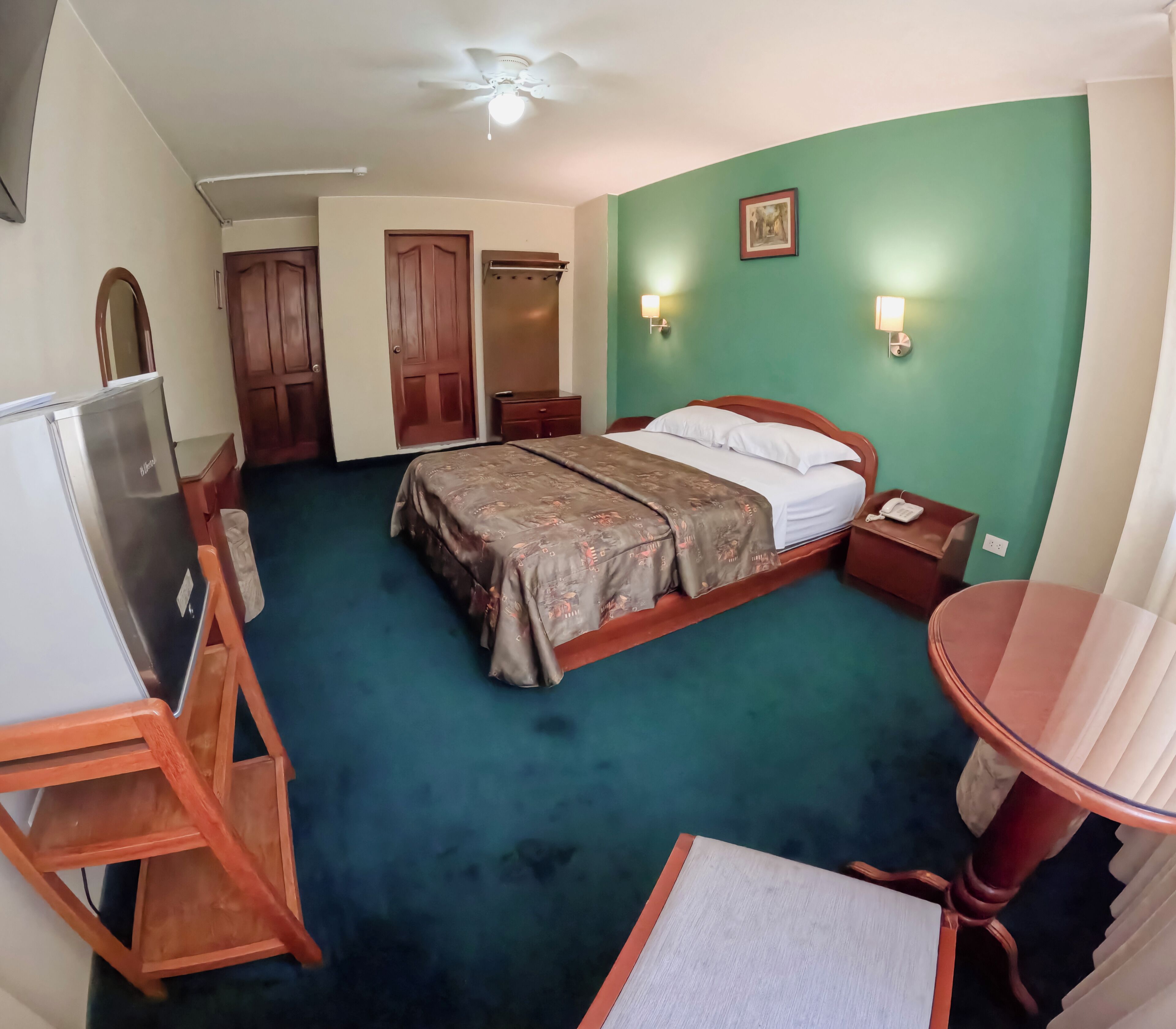 Una habitación de hotel con cama, mesita de noche, lámpara y escritorio con silla.