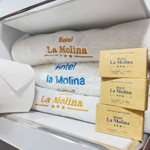 A hotel room with a white towel and three small boxes labeled 'Hotel La Molina'. - Hotel La Molina (La Molina)