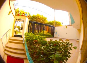 A curved staircase leading to a door labeled "SALIDA" with a metal gate, surrounded by greenery and a view of trees. - Hotel La Molina (La Molina)
