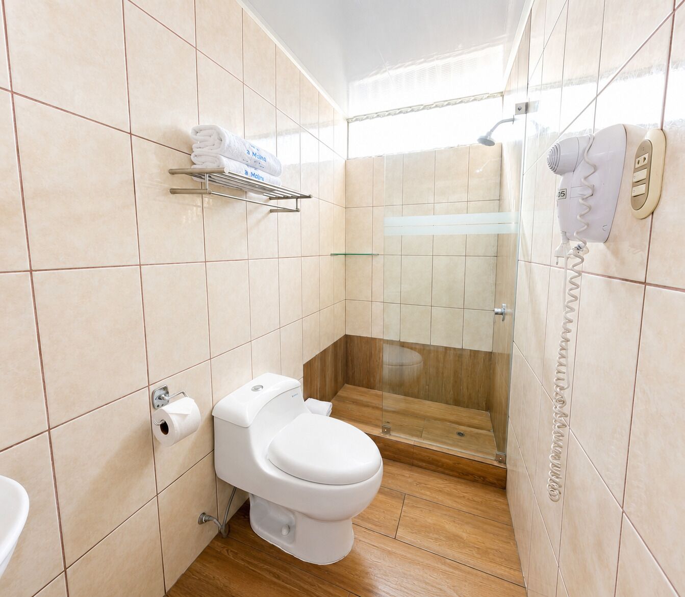 Een moderne badkamer met toilet, douchecabine van glas en een handdoekhouder.