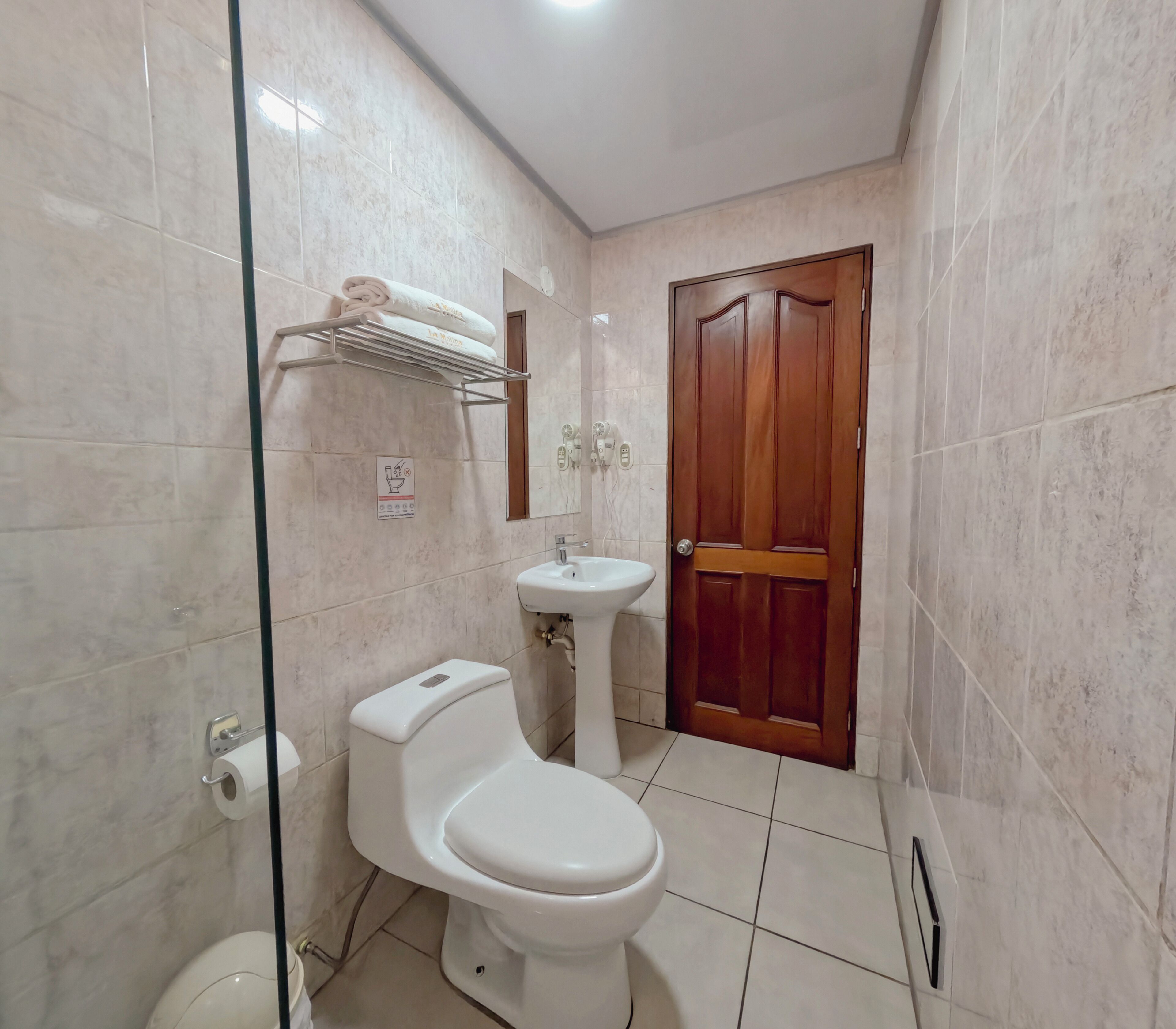Un baño con inodoro, lavamanos y perchero para toallas.