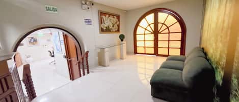 Un vestíbulo con mostrador de recepción, una escalera y un amplio ventanal de arco.