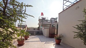 A rooftop terrace with potted plants, a flag, and a staircase leading to an upper level. - Hotel La Molina (La Molina)
