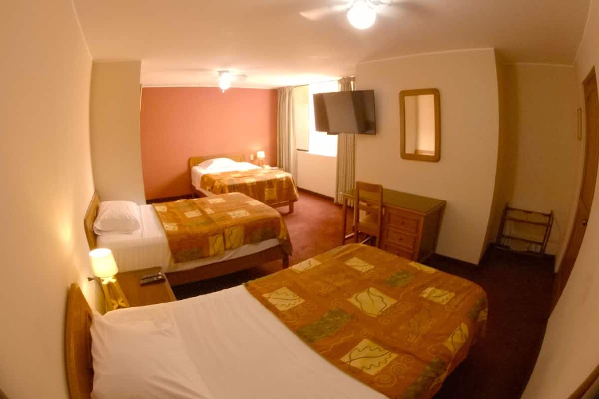 Ein Hotelzimmer mit zwei Betten, einem Fernseher, einem Schreibtisch und einem Sessel.
