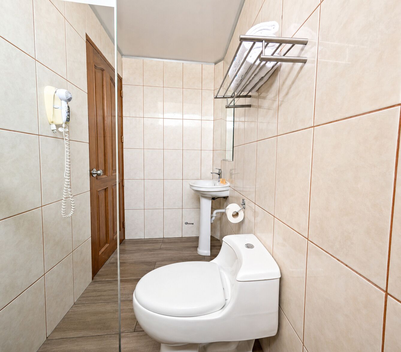 A small bathroom with a toilet, sink, and a hairdryer mounted on the wall.