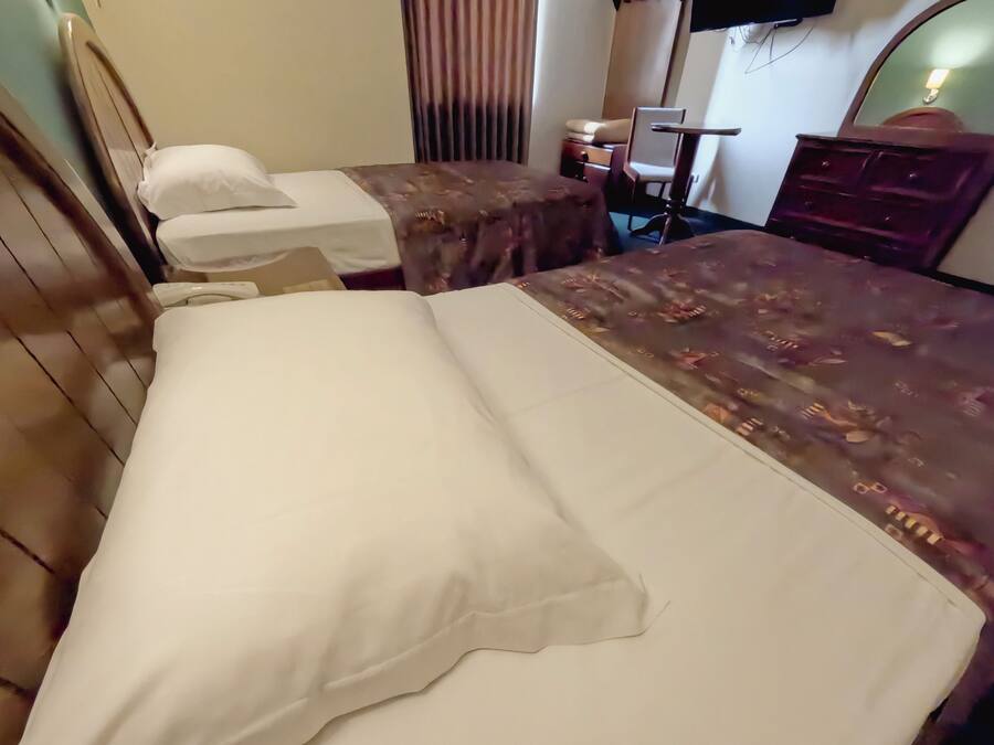 A hotel room with two beds, a television, a mirror, and a dresser.