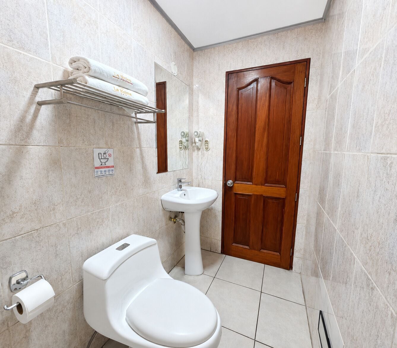Un bagno con il water, un lavandino e una porta in legno.