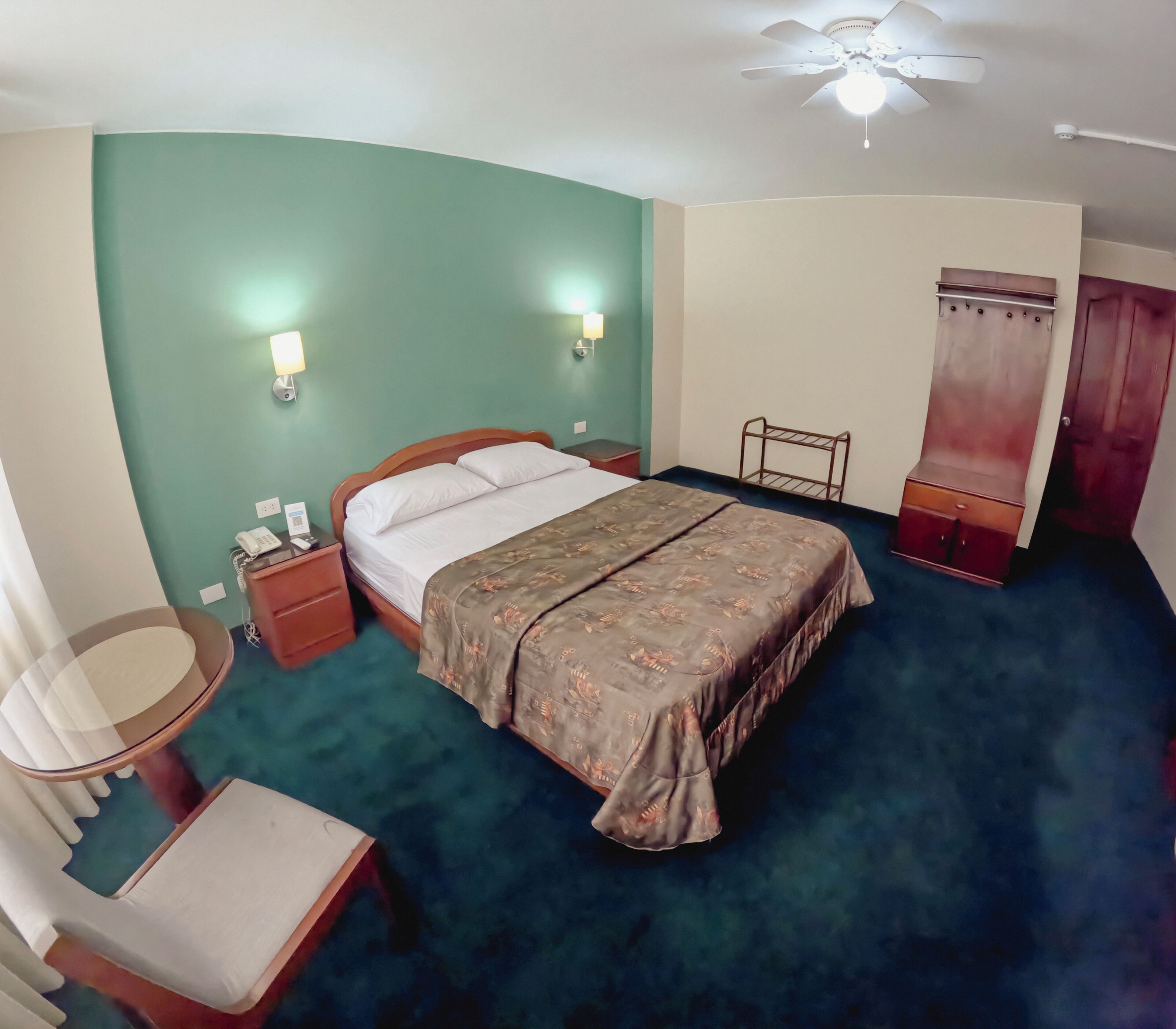 Ein Hotelzimmer mit Bett, Nachttisch, Lampe und Deckenventilator.