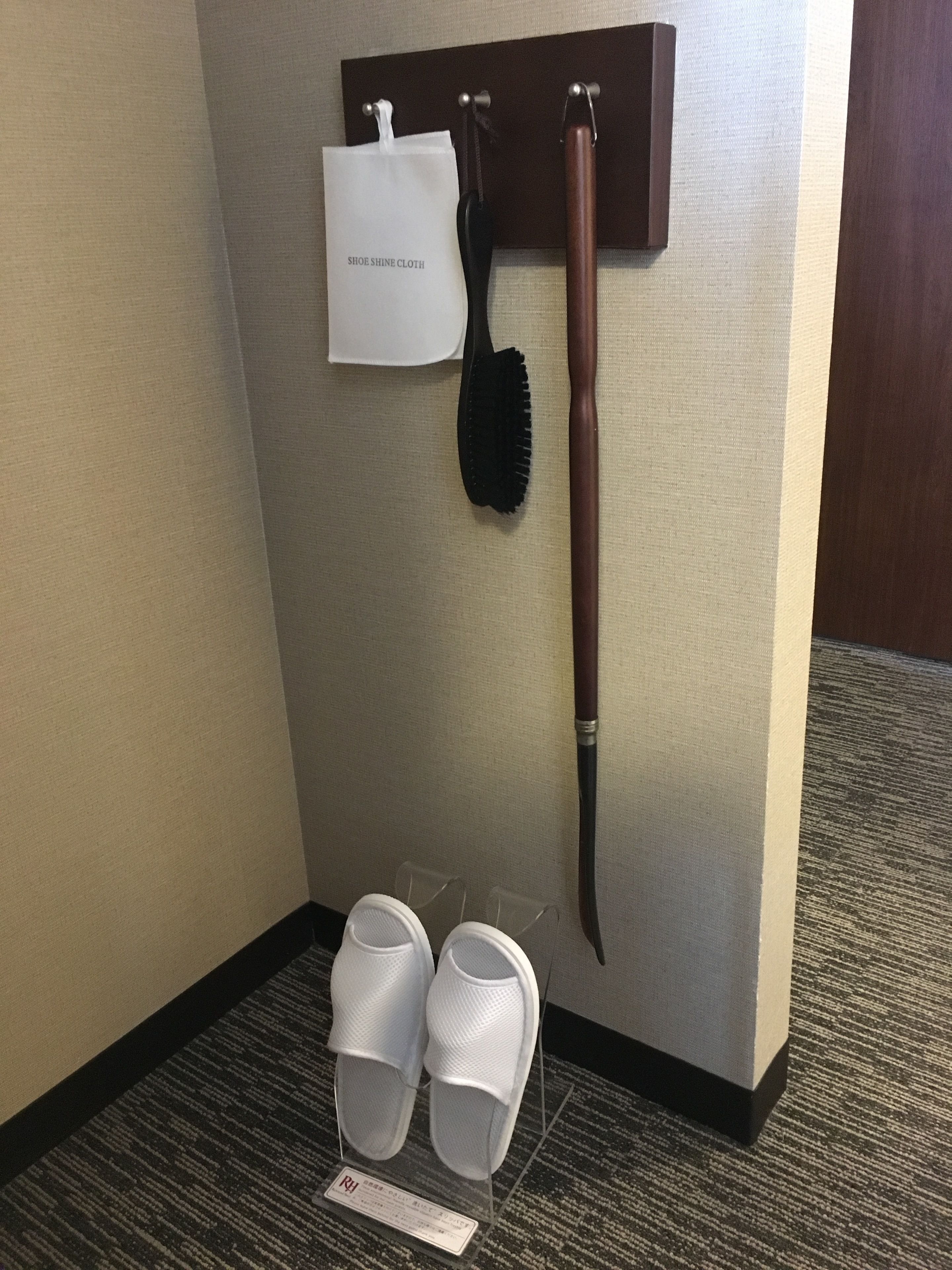 A hotel room with a shoe shine station, including a brush, polish, and a white bag labeled "Shoe Shine Cloth".