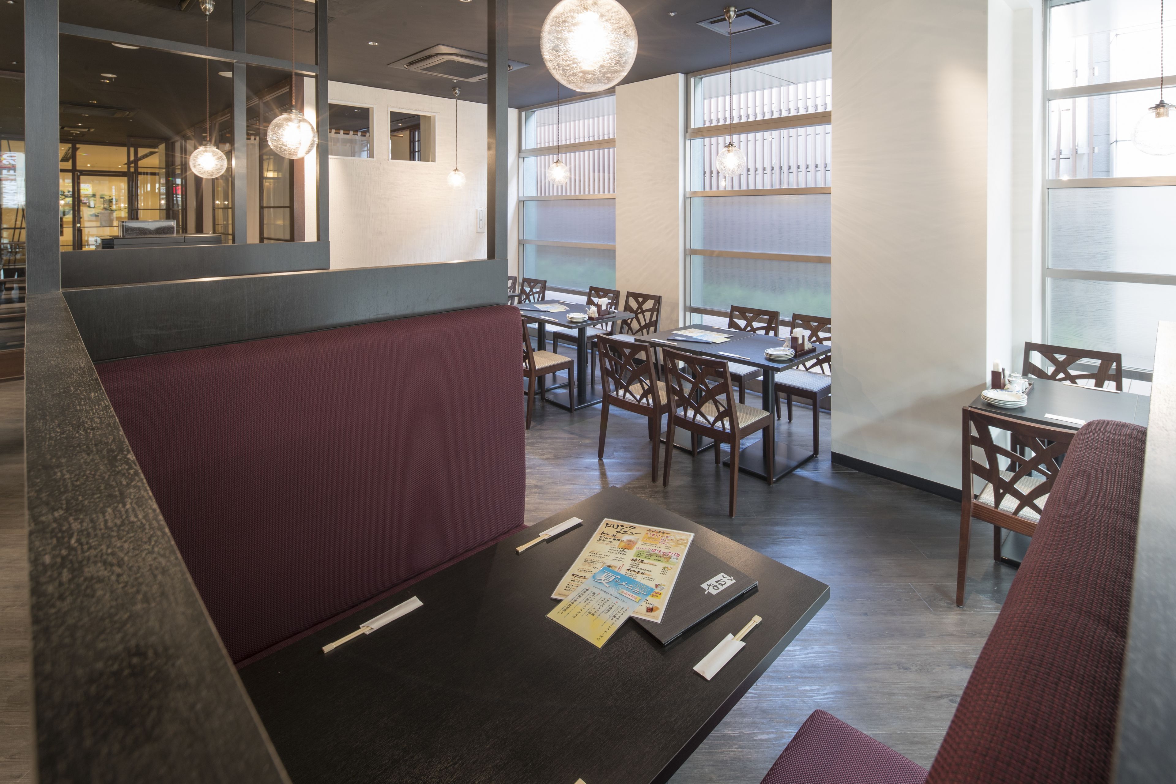 A restaurant with booths, tables, and hanging lights.