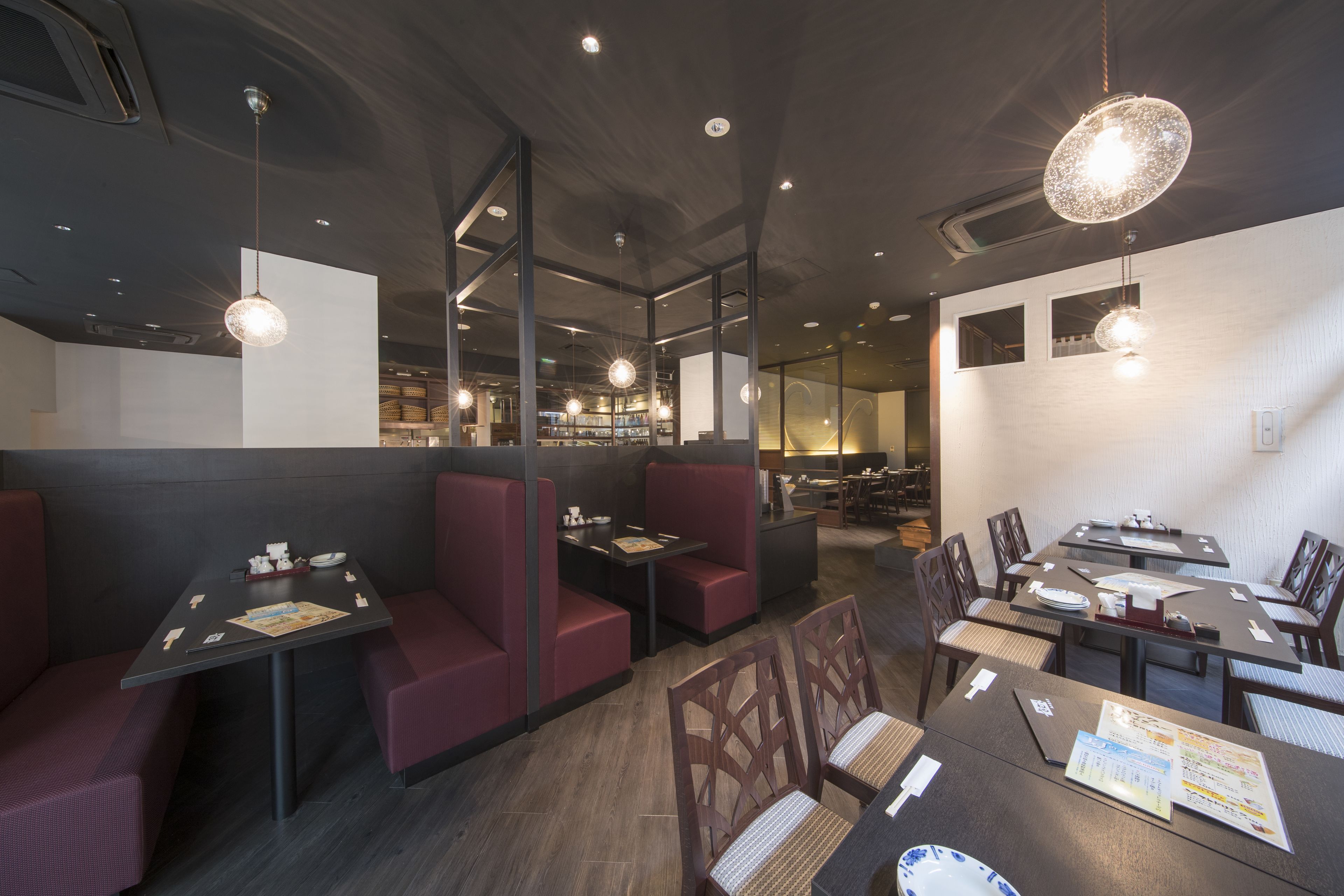 Un restaurant moderne avec des banquettes et des tables, doté d’un éclairage suspendu et d’un décor intérieur sombre.