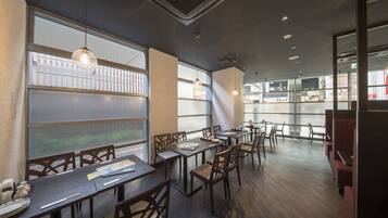 A restaurant with wooden tables and chairs, large windows, and a modern interior design.
