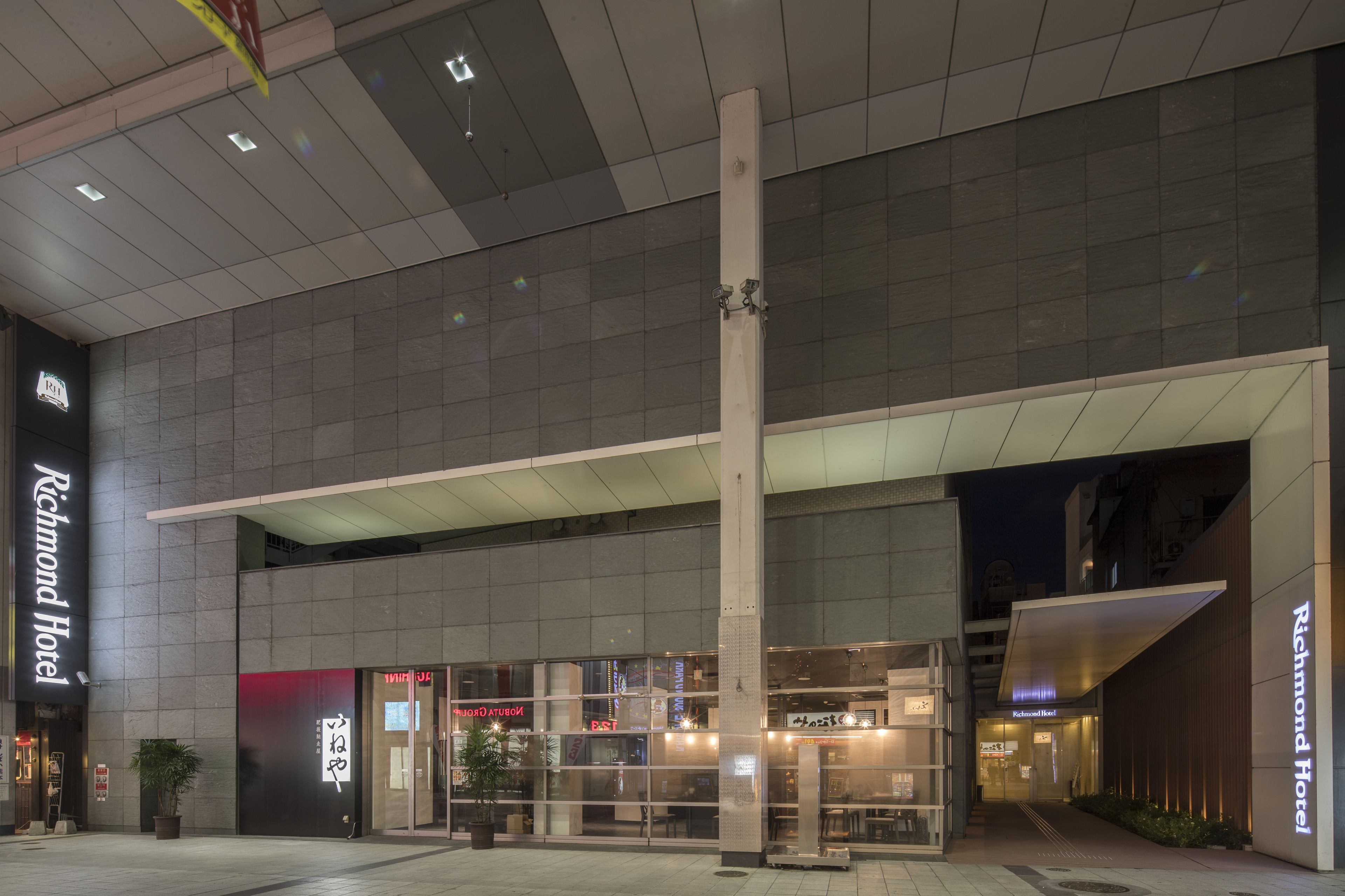 A hotel entrance with a modern design, featuring a large glass facade and a prominent sign for the Richmond Hotel.