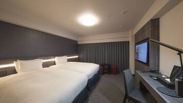 Une chambre d’hôtel moderne avec un grand lit, un bureau équipé d’un ordinateur et un téléviseur fixé au mur.