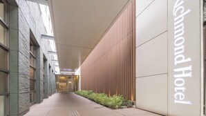 A corridor with a 'Richmond Hotel' sign, a modern building facade, and a pathway with plants. - Richmond Hotel Kumamoto Shinshigai (Kumamoto)