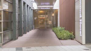 The entrance to Richmond Hotel with a modern design, featuring a glass door and a wooden pathway leading to the entrance. - Richmond Hotel Kumamoto Shinshigai (Kumamoto)