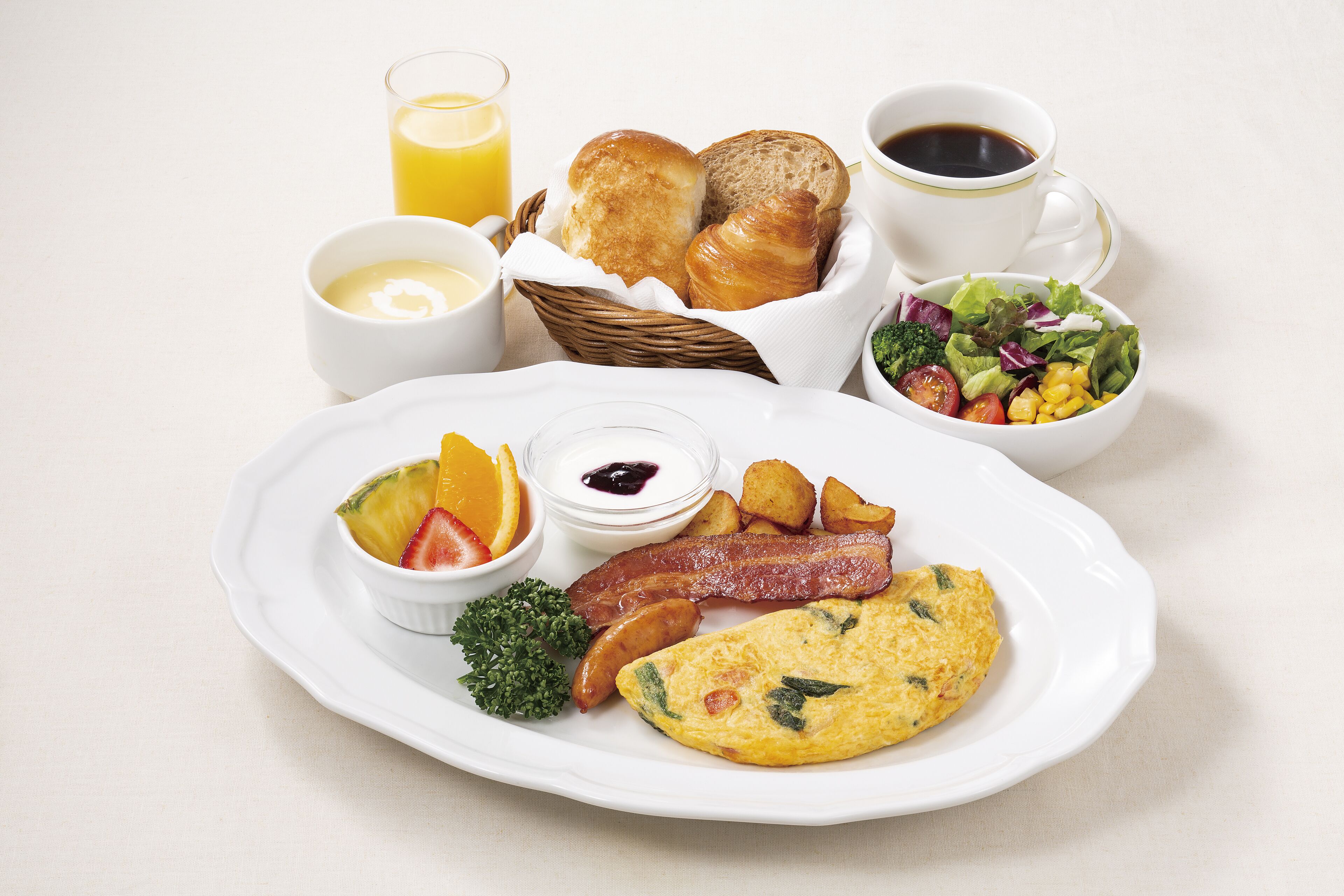 A breakfast plate with eggs, bacon, potatoes, and a fruit salad.
