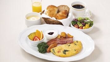 A breakfast plate with eggs, bacon, potatoes, and a fruit salad.