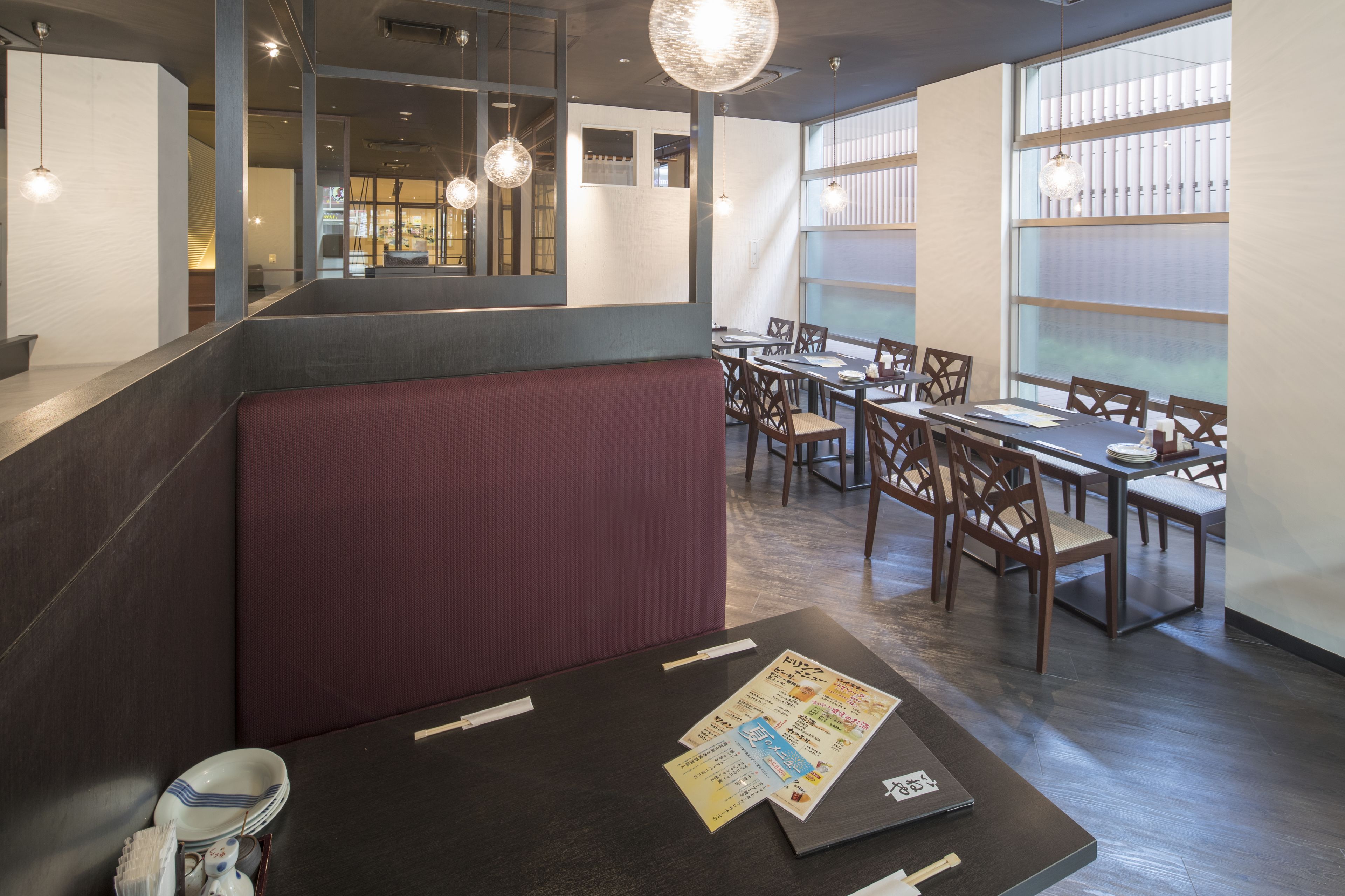 Ein Restaurant mit Sitzbänken und Tischen, einer Speisekarte auf dem Tisch und hängenden Lampen.