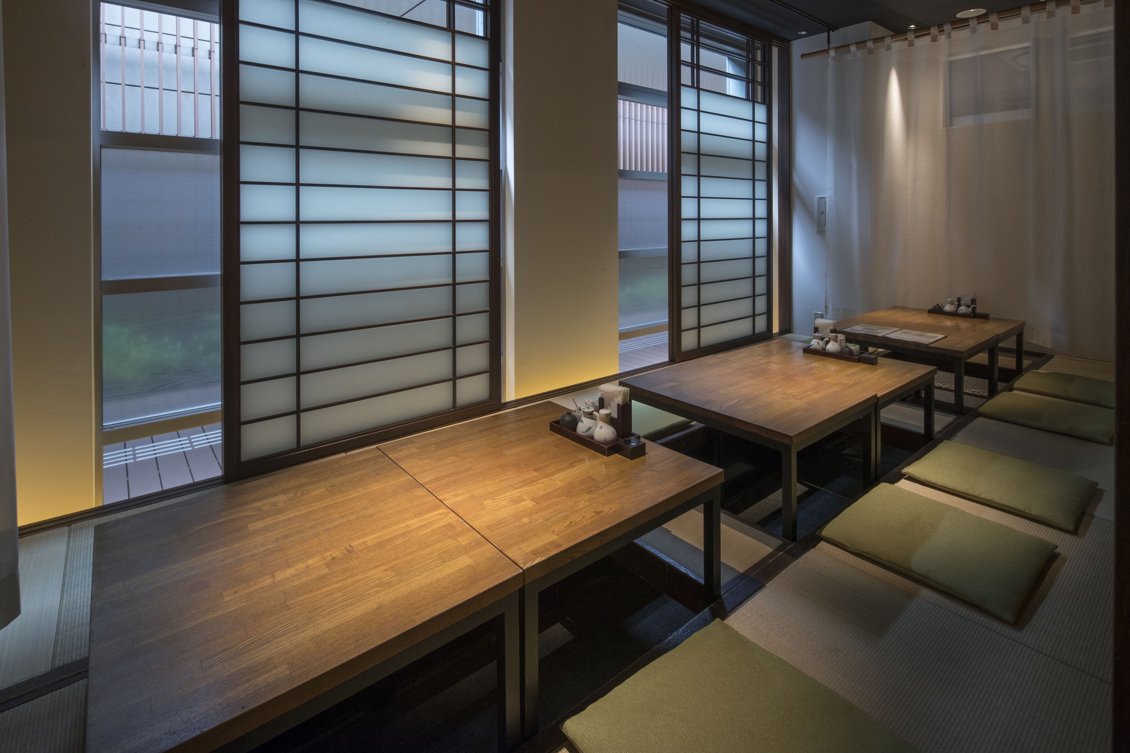 A traditional Japanese-style room with tatami mats, sliding doors, and a wooden table with cushions.