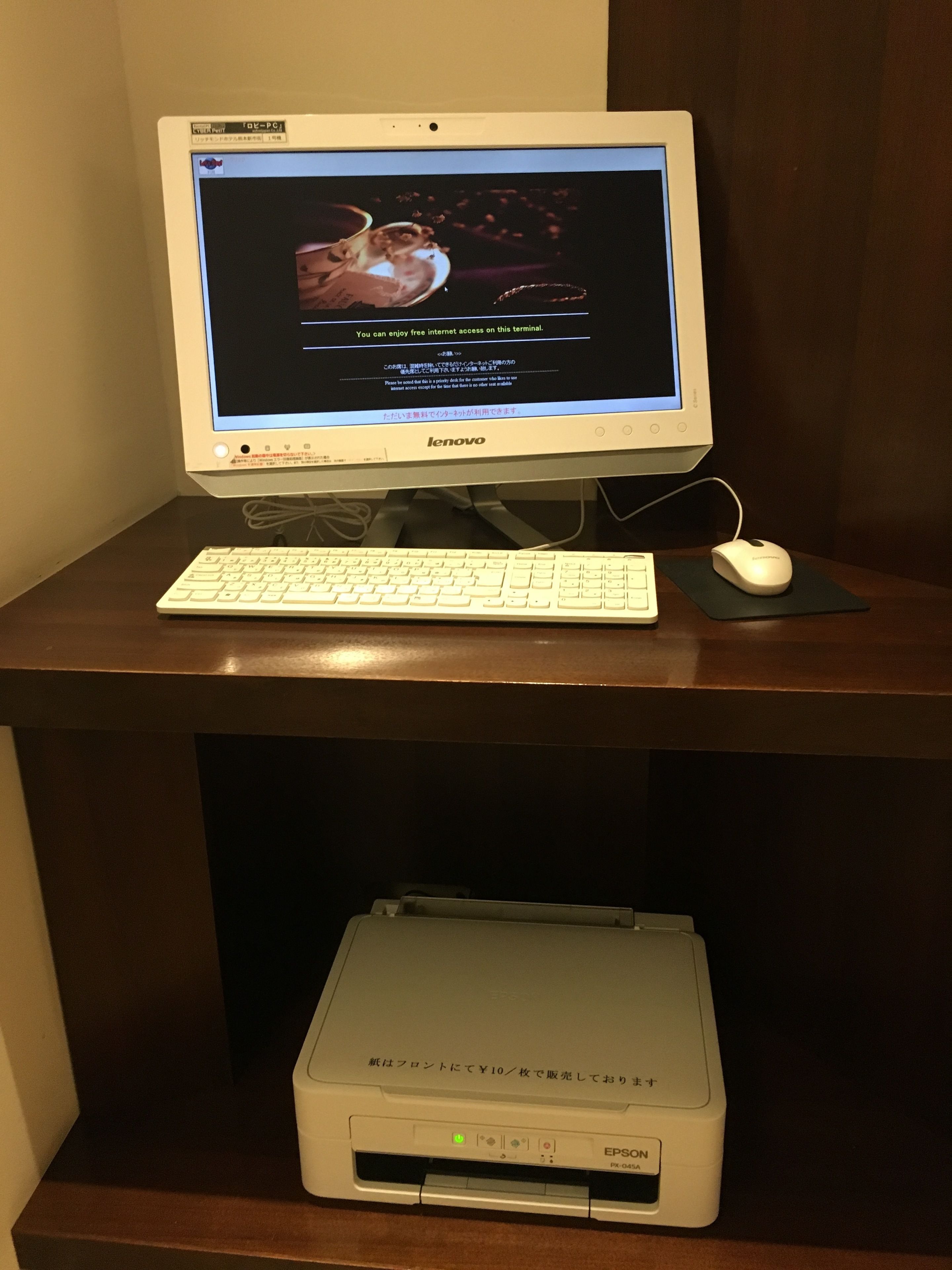 A Lenovo desktop computer with a keyboard and mouse on a wooden desk. Below the desk, there is an Epson printer.