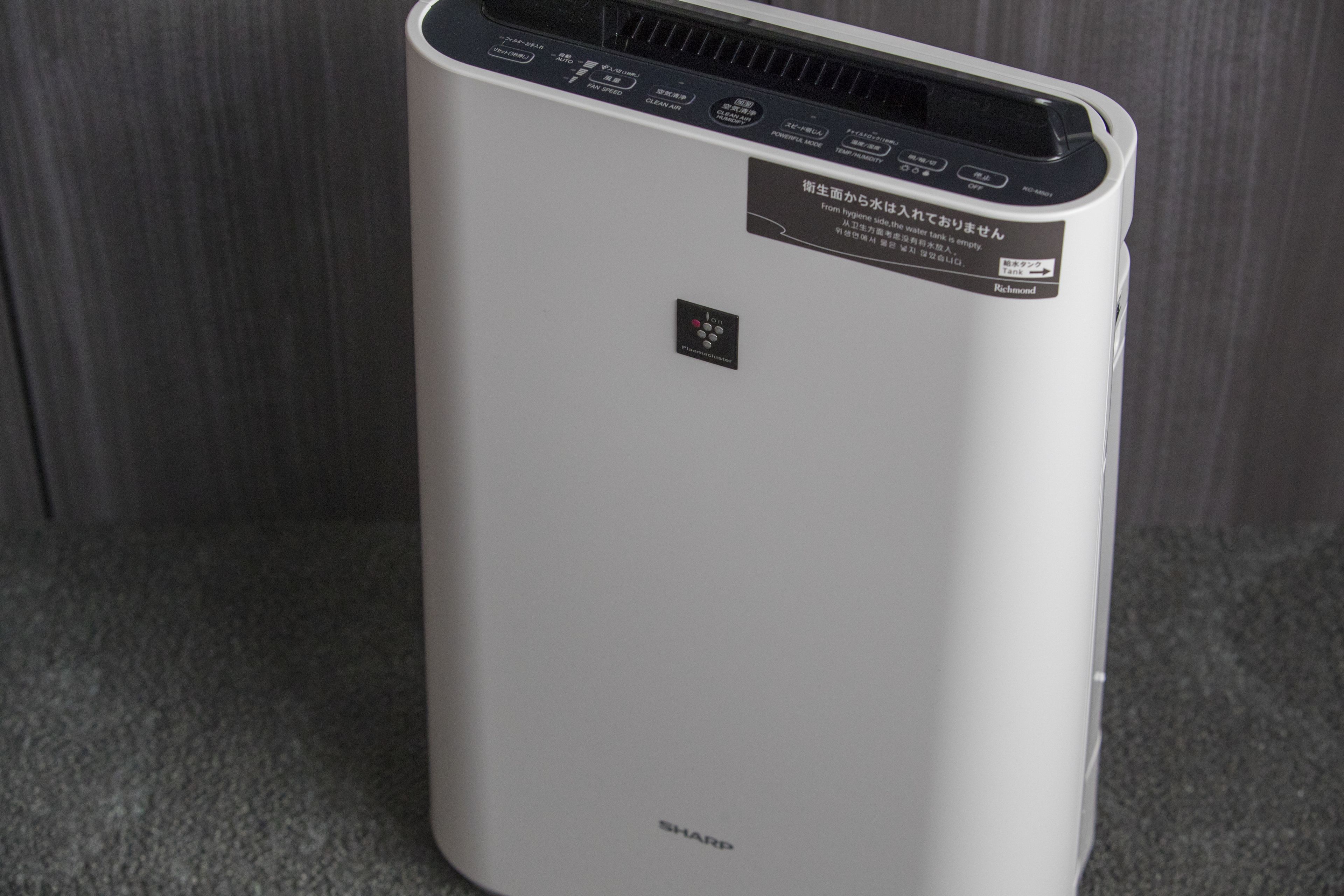 A white portable air purifier with a control panel and a label in a foreign language.