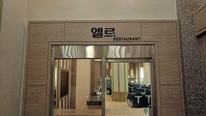 L’entrée d’un restaurant au design moderne, avec une façade en bois et des portes en verre.