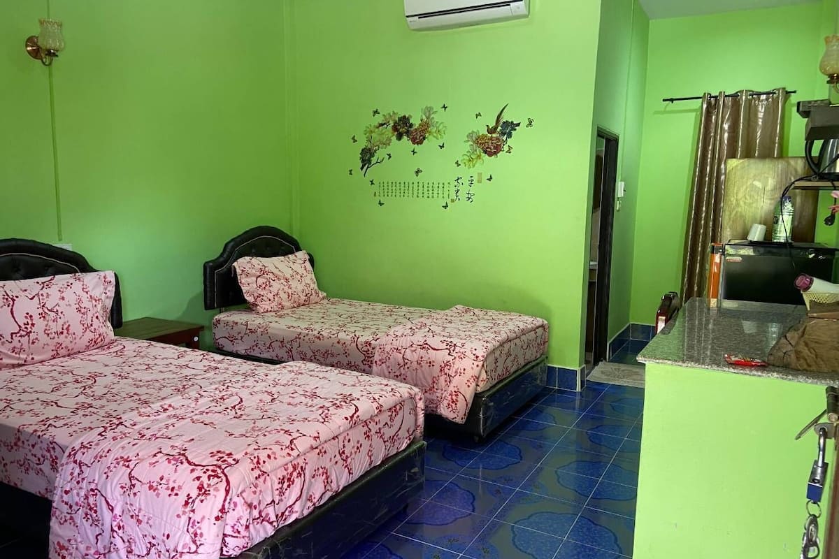 A room with two beds, a kitchenette, and a bathroom.