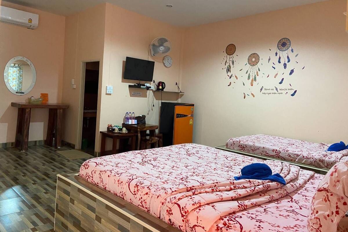 A hotel room with two beds, a TV, a desk, and a wardrobe.
