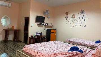 Habitación de hotel con dos camas, televisión, escritorio y armario.