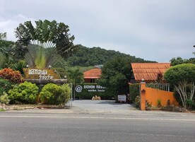 Entrada de un hotel con un cartel, una puerta y montañas al fondo.