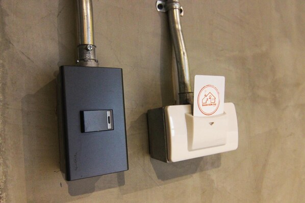 Two wall-mounted switches, one black and one white, with a red icon on the white switch. - Baan Kon Pai - Hostel (Pai)