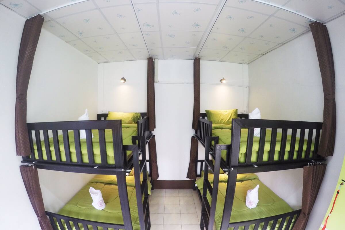 Una habitación con literas, cada una con colchón verde y estructura de madera.